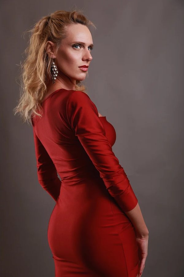 Il risultato dello scatto: Laura in sala posa, in abito rosso a maniche lunghe, su fondale grigio
